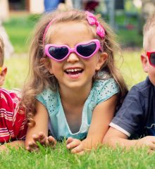 três crianças sorridentes de óculos escuros